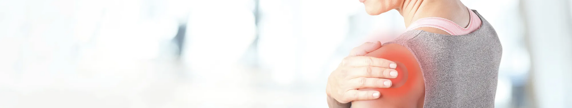 Frau fasst sich an die schmerzende Schulter