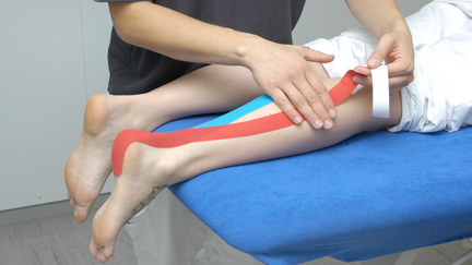 Eine Person liegt auf einer Liege und wird am Bein behandelt