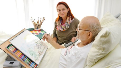 Kunsttherapeutin malt mit Patienten ein Bild 