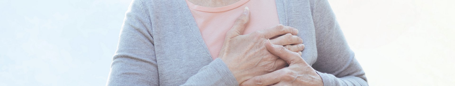 Frau hält sich schmerzhaft die Hand aufs Herz